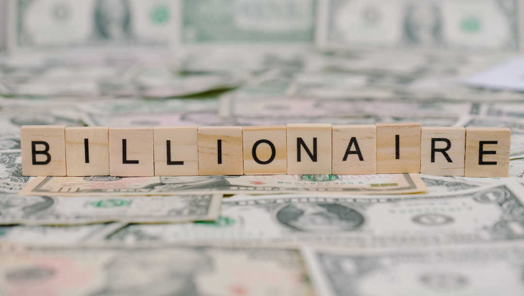 Scrabble tiles spelling “billionaire” on top of dollar notes