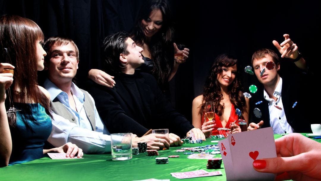 a group of friends at a green felt poker table in a casino playing poker and socializing