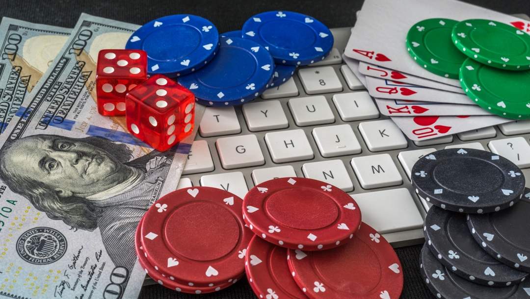 Casino chips, cash, playing cards and dice on a keyboard.