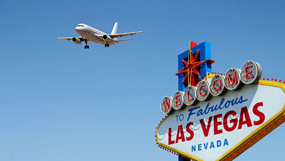 view of an airplane flying above the “Welcome to Fabulous Las Vegas Nevada” sign with blue skies