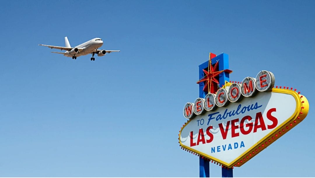 “Welcome to Fabulous Las Vegas Nevada” sign during the day with an airplane flying forward in the distance
