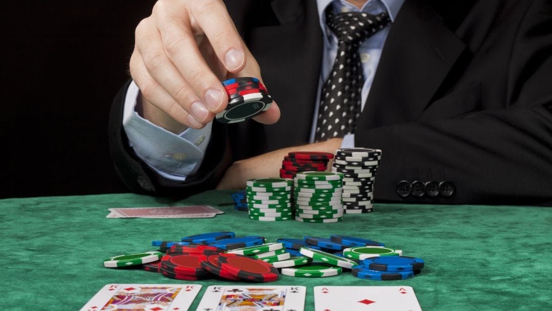 a man in a suit placing a bet during a poker game on a green felt surface