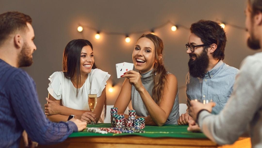 Header image, friends sitting around a poker table laughing and playing poker