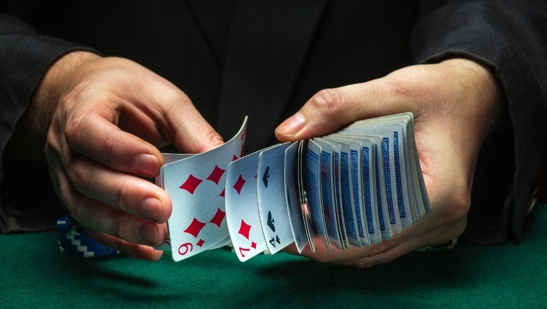 a man shuffling playing cards above a green felt poker table