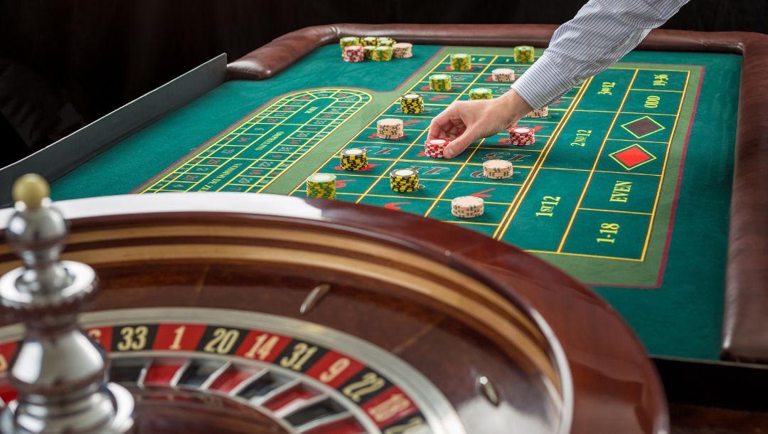 a man placing a stack of chips on a roulette table making a bet in the casino