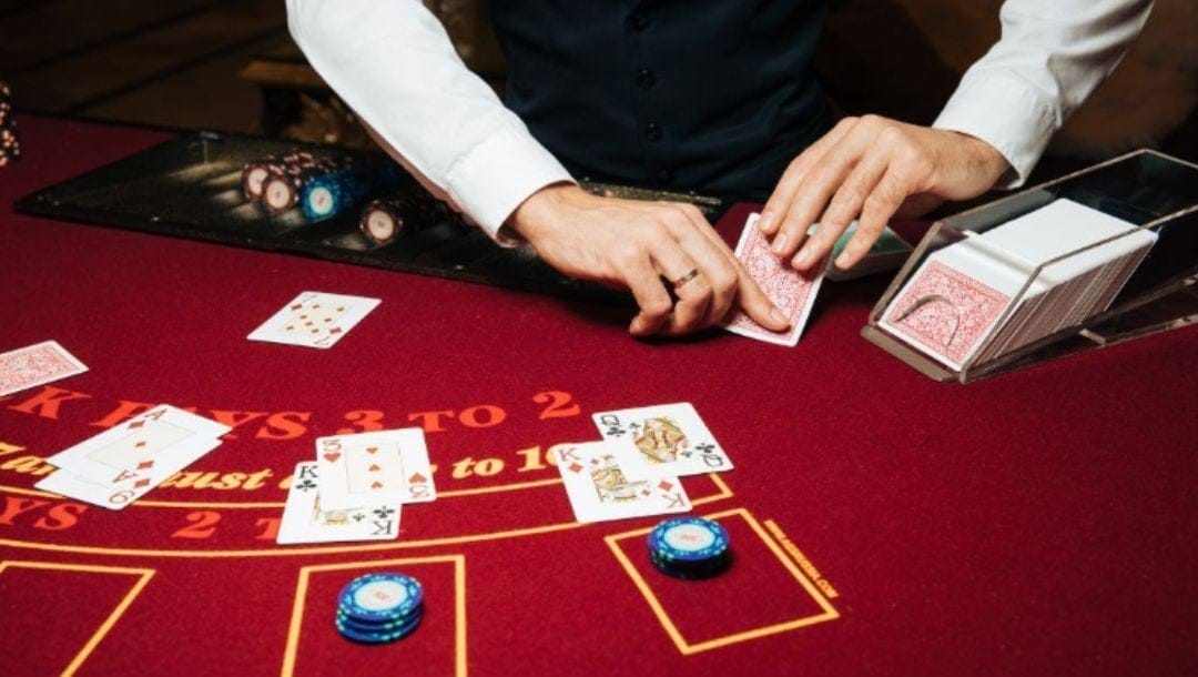 a dealer dealing cards at a red blackjack table in a casino