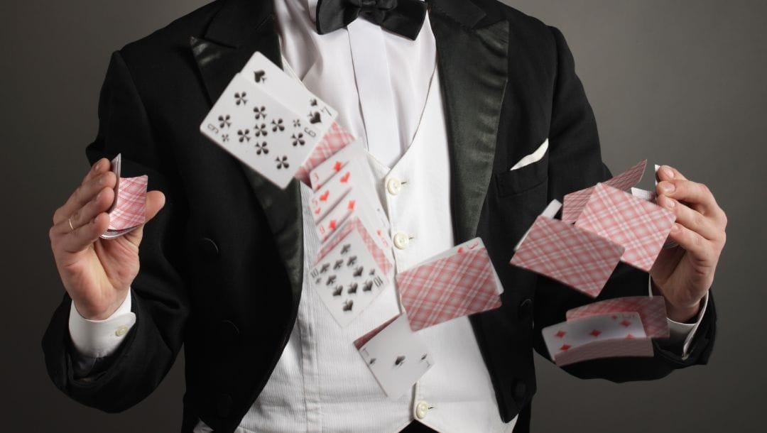 a man in a suit and bowtie shuffling cards in the air