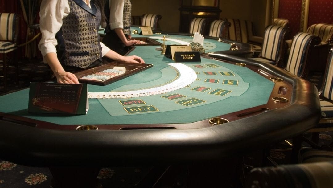 casino dealers standing at two adjacent blackjack poker tables in a casino