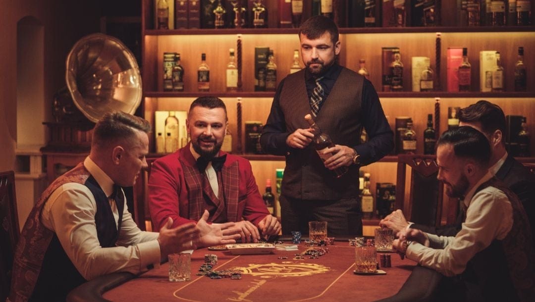 Header image, five well dressed men around an intimate setting poker game, shelves of bottles in the background