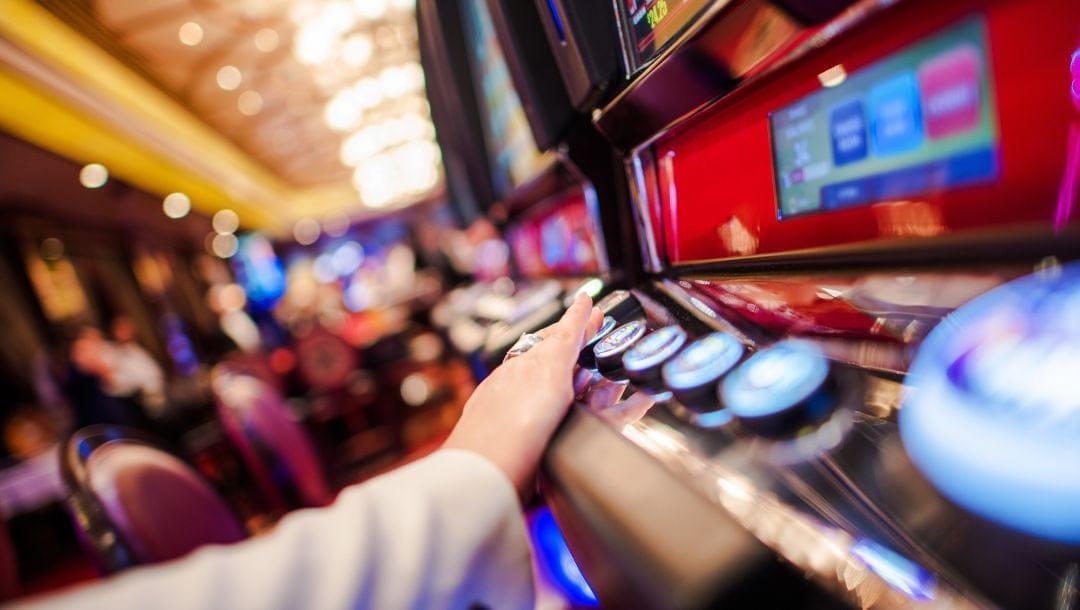Header image, close up of someone playing on a casino game machine pressing a button