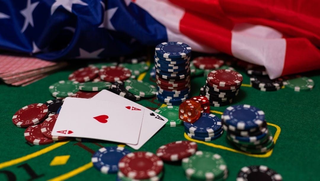poker chips and playing cards on a green felt poker surface with an American flag laying on the table