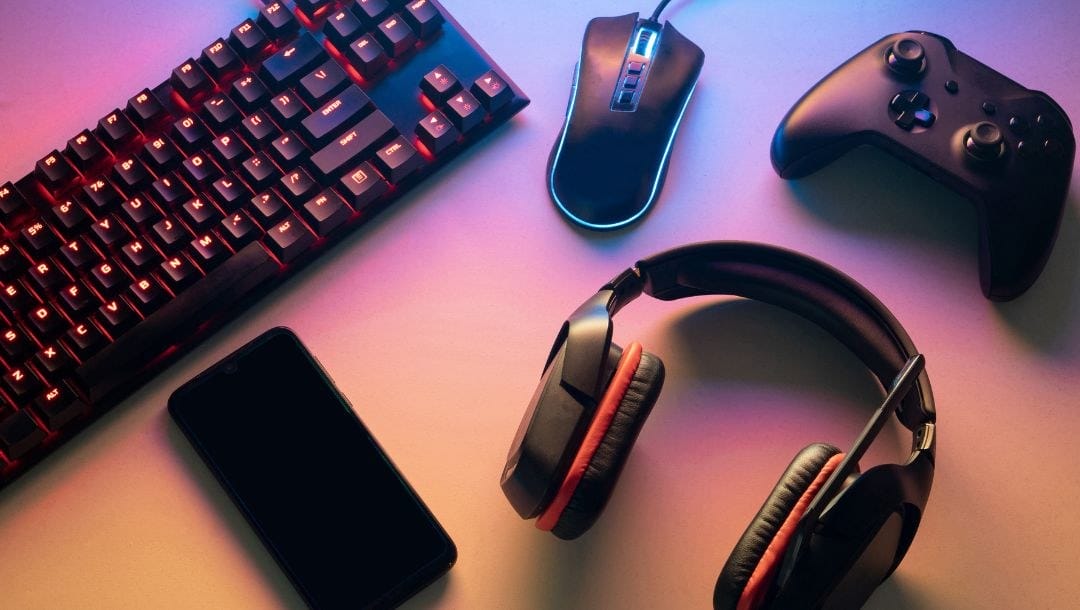 gaming technology - a keyboard, cellphone, headset, computer mouse and gaming console on a desk