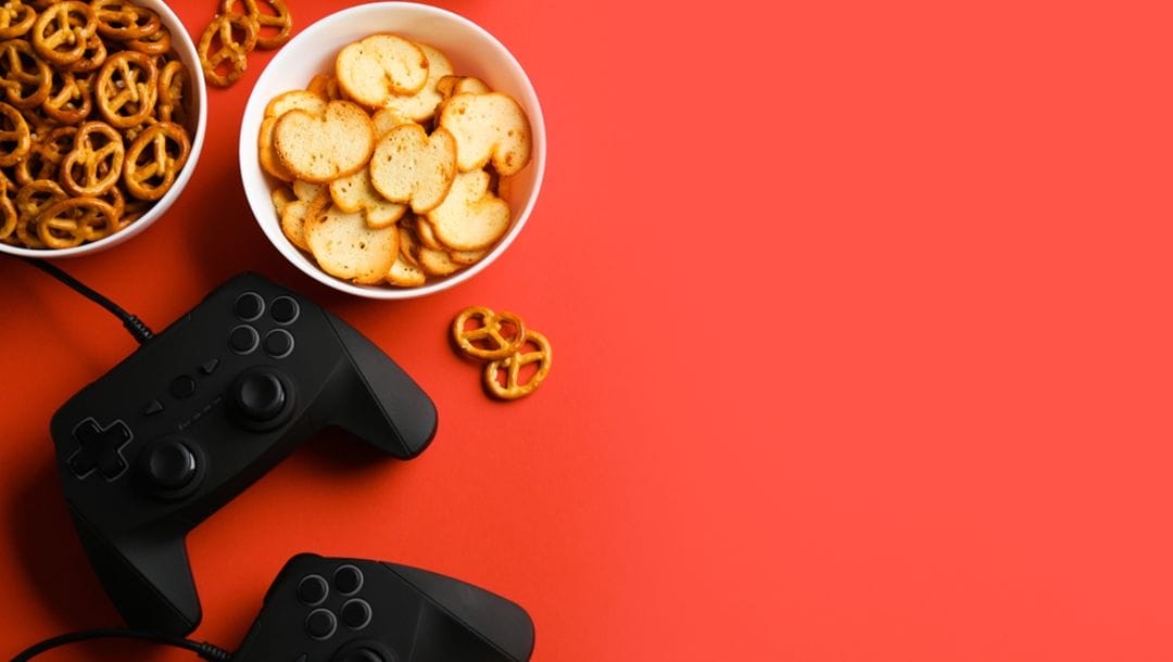 Mini pretzels and chips in bowls next to gaming consoles.