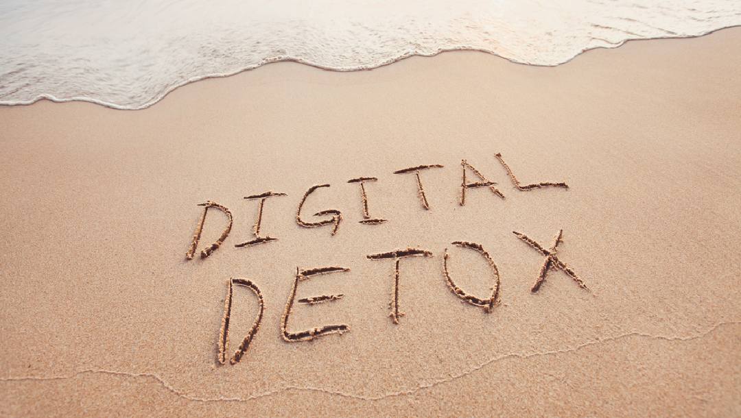 “Digital Detox” written in the sand on a beach