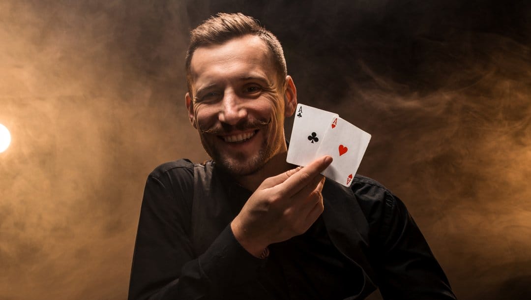 A well-dressed gambler smiles and holds up two aces.