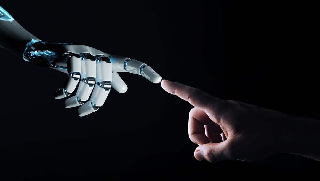 A robot hand and a human hand pointing at each other with the fingertips of their pointing fingers almost touching.
