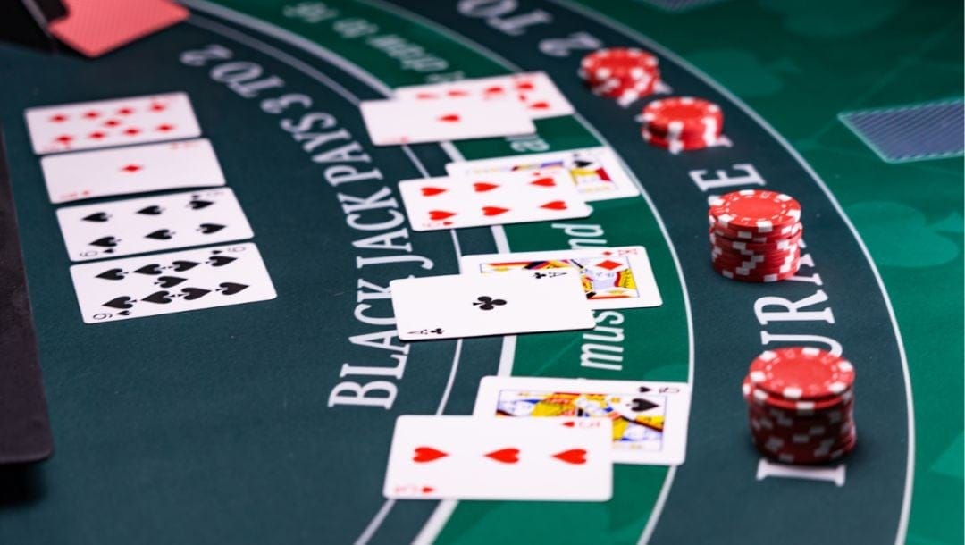 playing cards laid out face up on a blackjack table in a casino with red poker chips in front of each hand