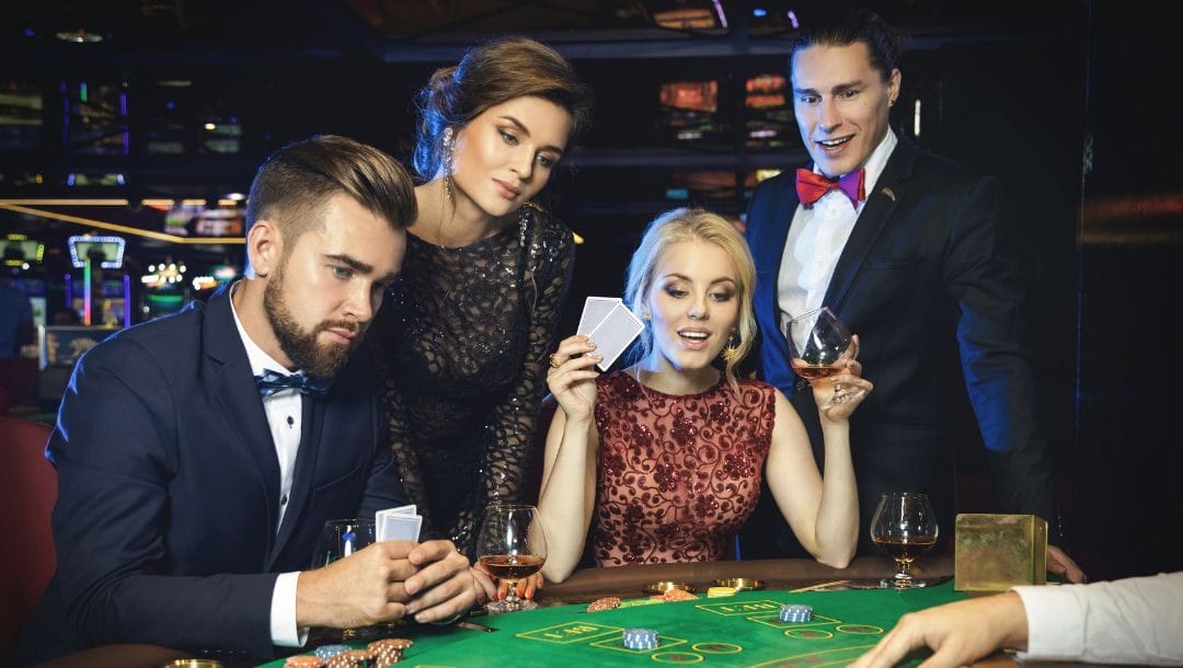 four friends are sitting at a blackjack table in a casino drinking and playing blackjack