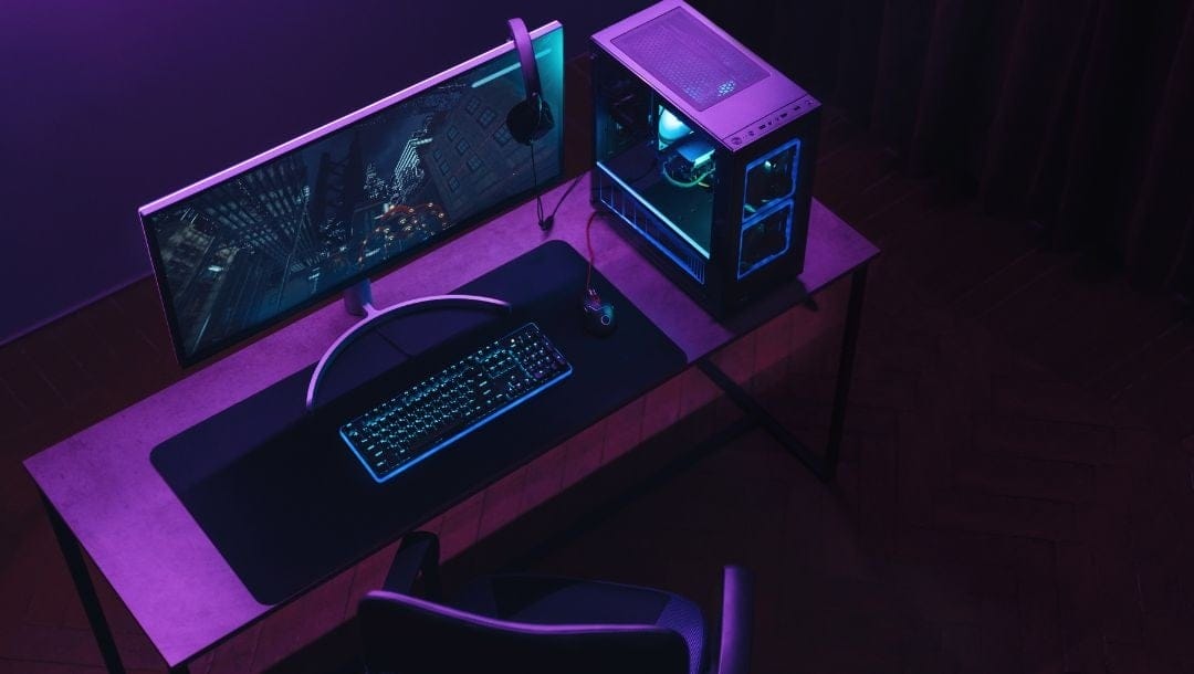 a gaming setup of a gaming chair and desk with a desktop computer, keyboard, computer mouse and gaming headset on it