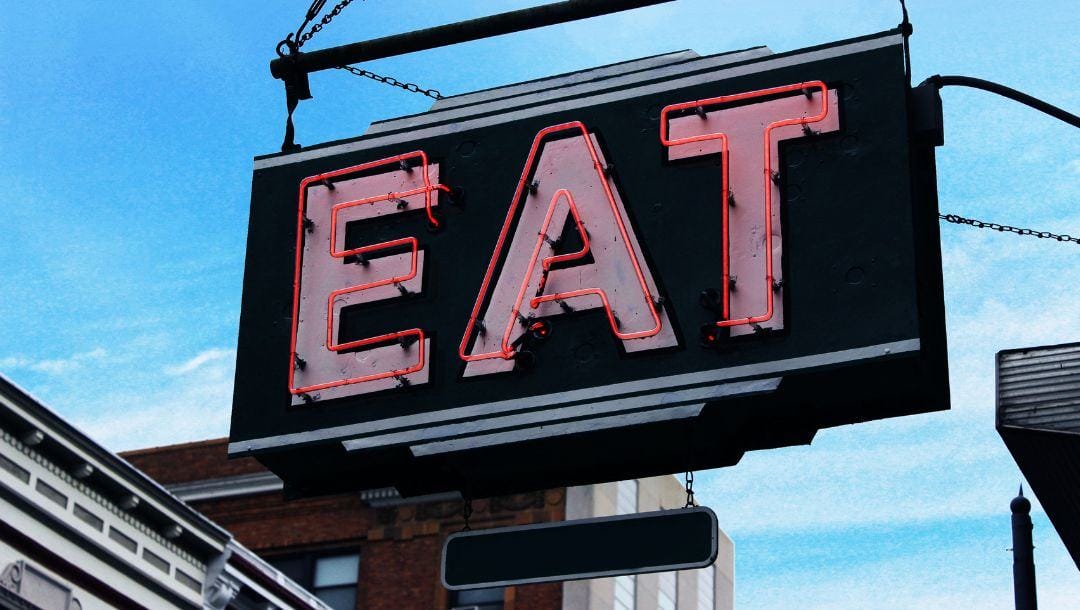 a neon restaurant sign that says “eat”