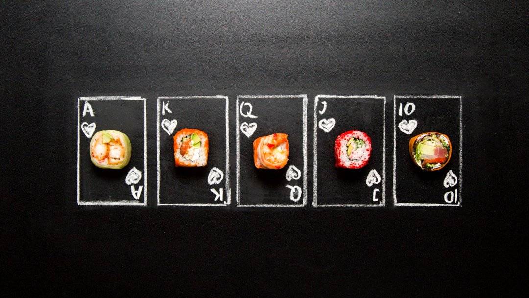 Different pieces of sushi placed on chalk drawings of playing cards.