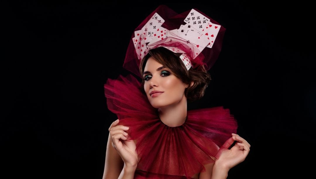a woman dressed up in maroon tulle fabric costume with an oversized collar and playing cards on her head