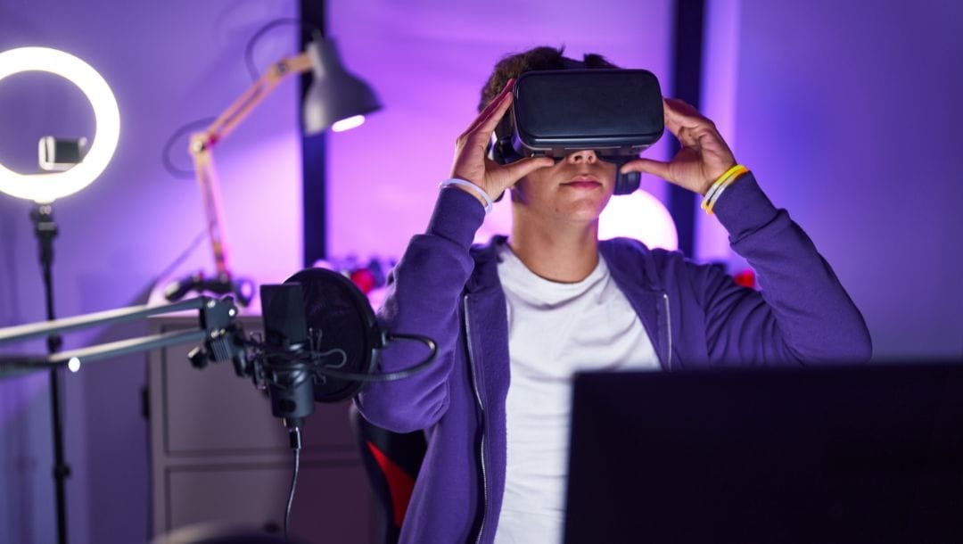 a person with a VR headset on as well as a microphone, ring light and lamp in front of them in a purple light room