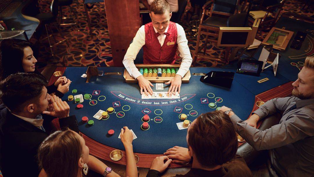an aerial view of five players and a dealer sitting around a blackjack table in a casino playing blackjack