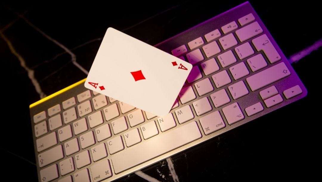 a computer keyboard with an ace of diamonds playing card standing on top of it