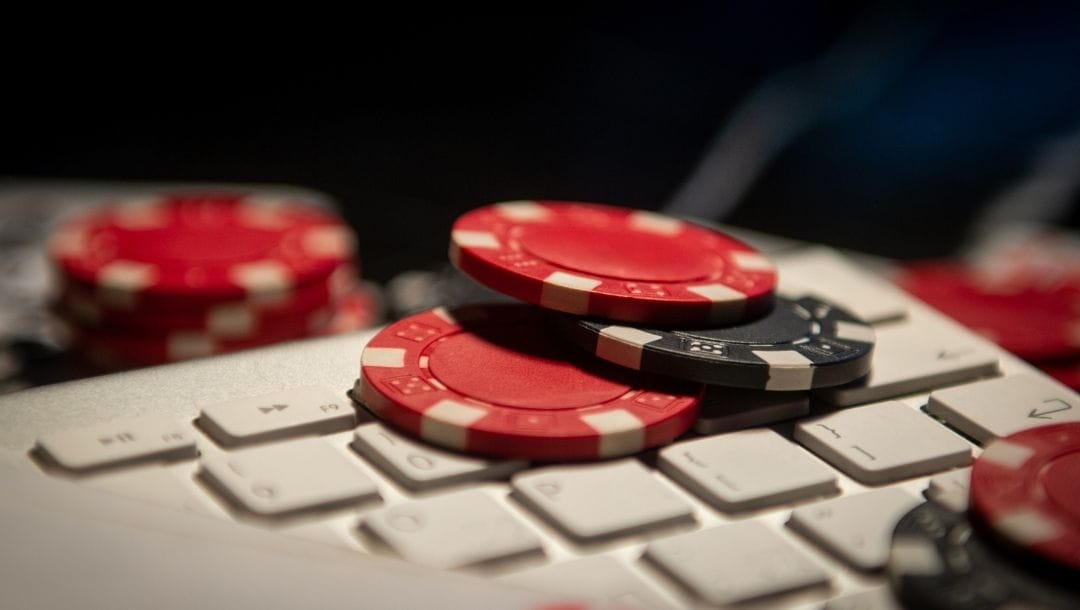 red and black poker chips on a white computer keyboard