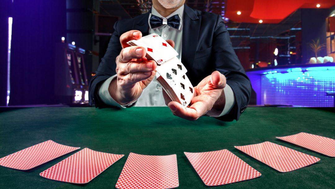a dealer shuffling a pack of playing cards at a green felt poker table in a casino
