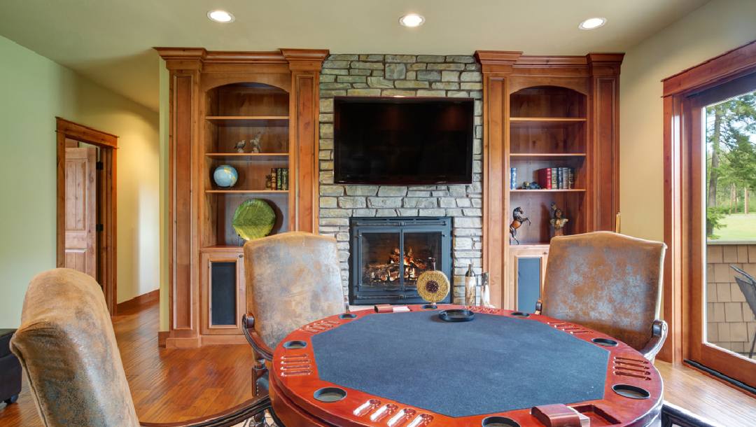 A round card games table in a front room with a TV and fireplace