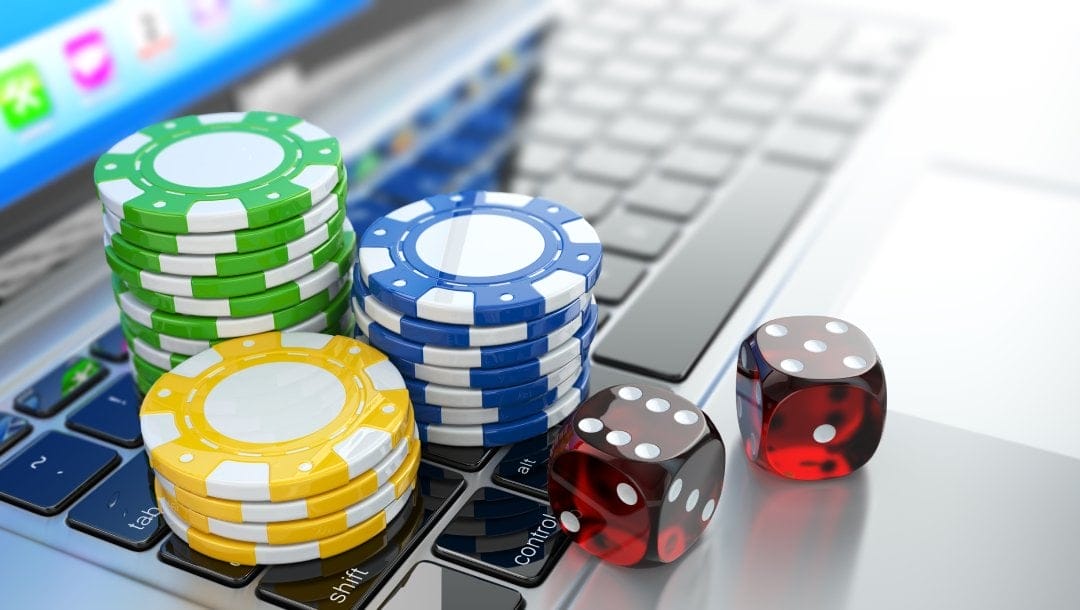 Casino chips and dice on a laptop keyboard.