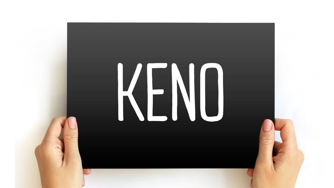 A person holding up a sign that says “Keno.”