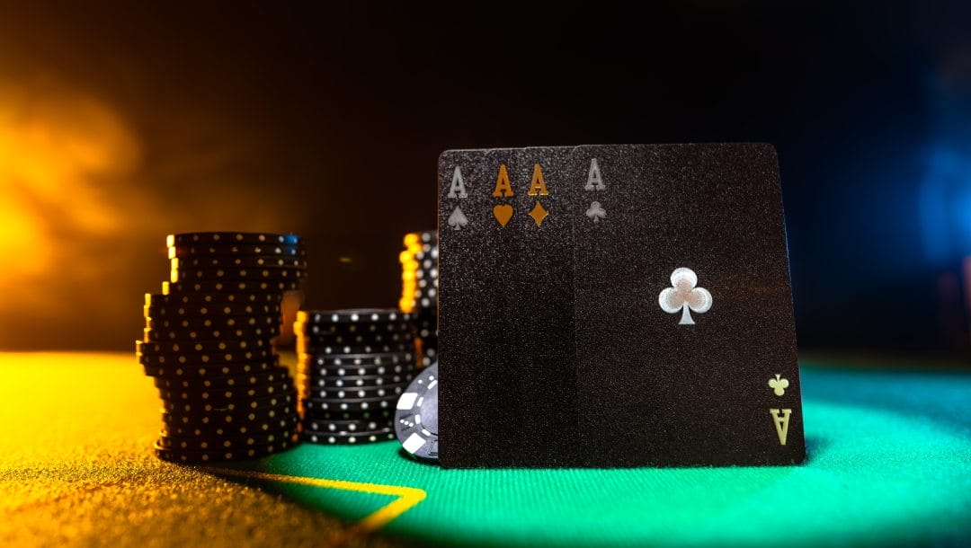 Black ace cards and black poker chips on a green felt table.