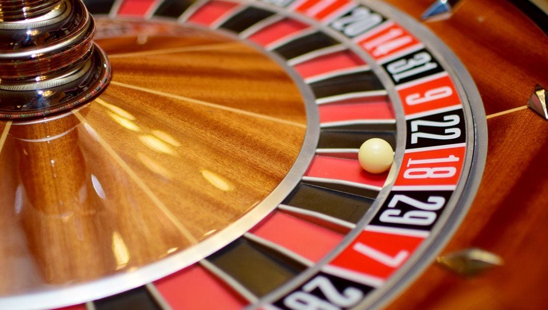 A close up of a roulette wheel. The roulette ball sits in the red 18 pocket.