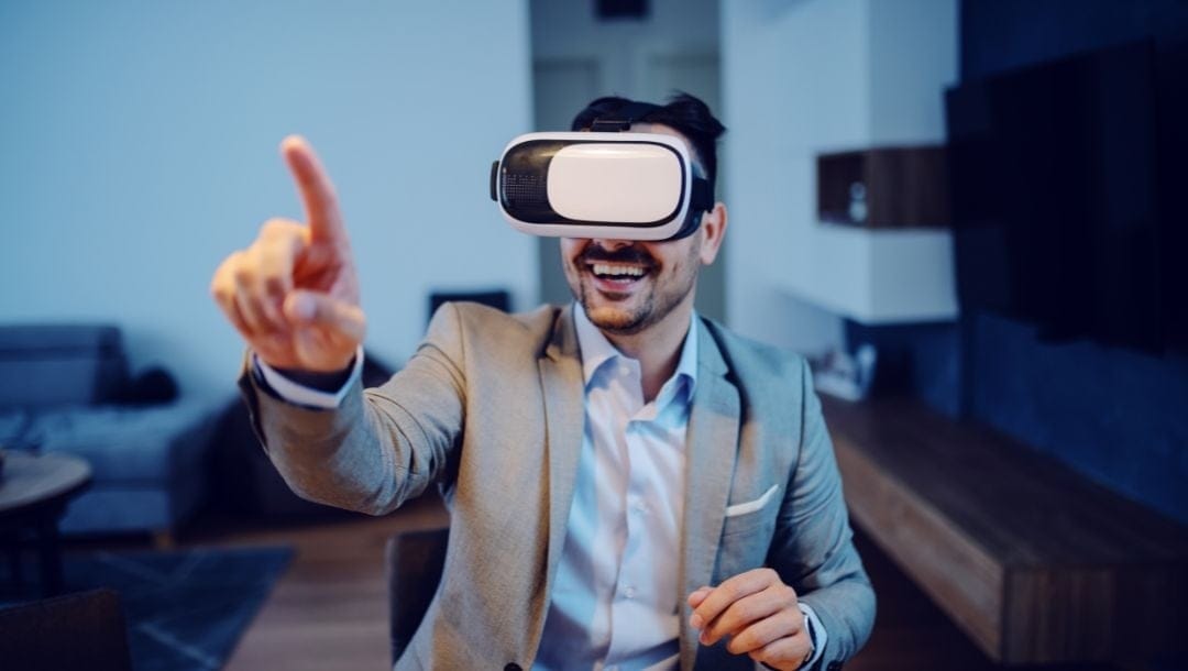 a man is smiling and pointing forward while wearing a virtual reality headset in his home