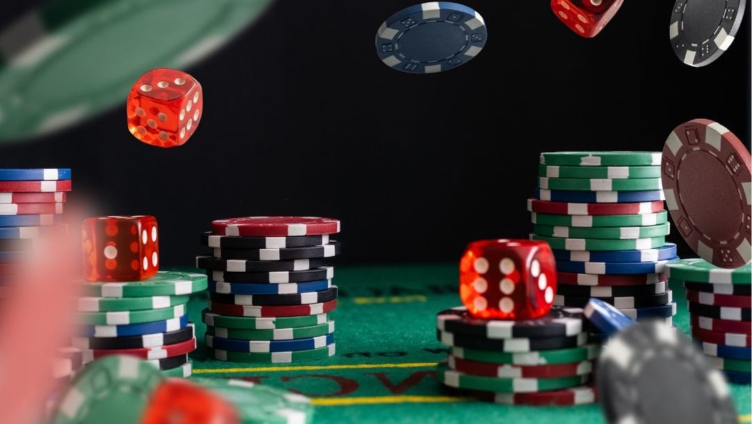 stacks of poker chips on a green felt poker table with other poker chips and red six-sided dice falling in the air