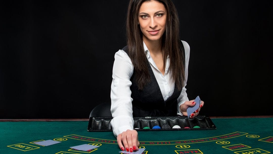 A female casino dealer dealing cards on a blackjack table.