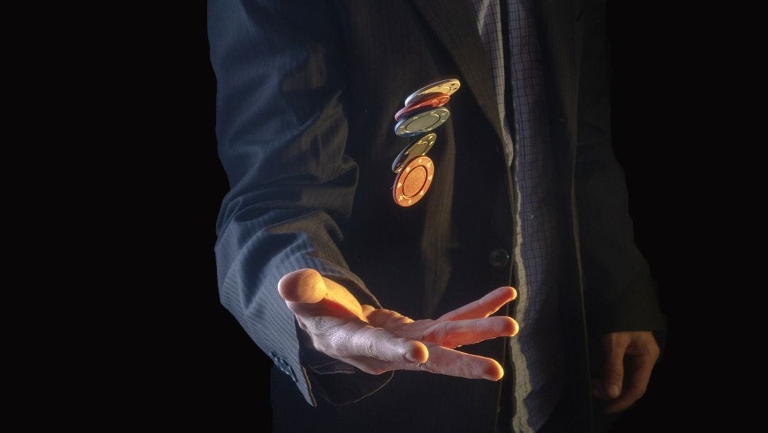a man wearing a suit is throwing poker chips up in the air with one hand