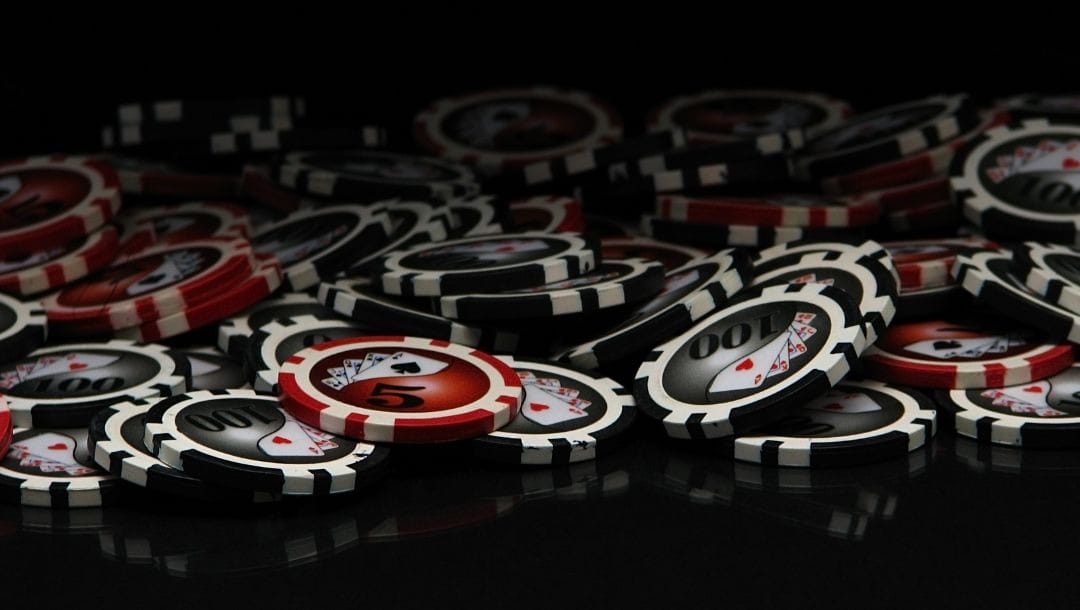 red and black poker chips on a black surface