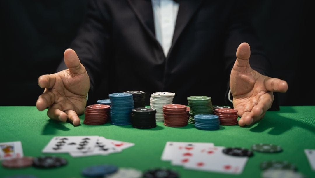 a man with his hands on a green felt poker table with poker chips and playing cards on it
