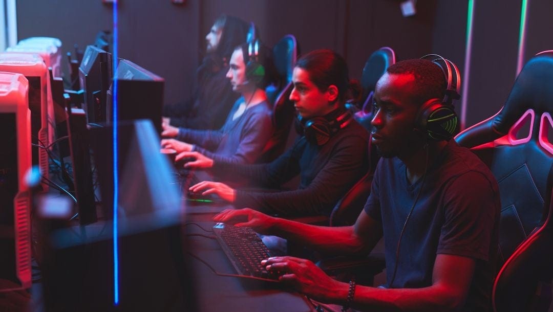 esport gamers sitting in a line next to each other playing games on computers with headsets on
