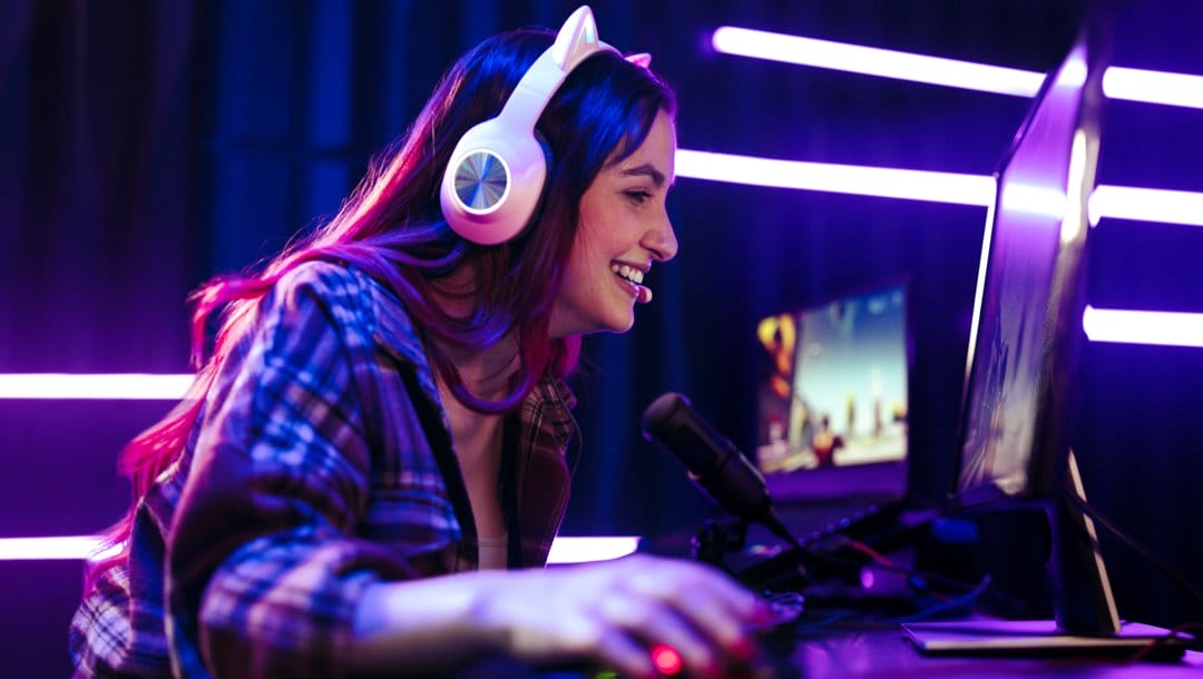 A person smiles while playing games on their gaming computer.