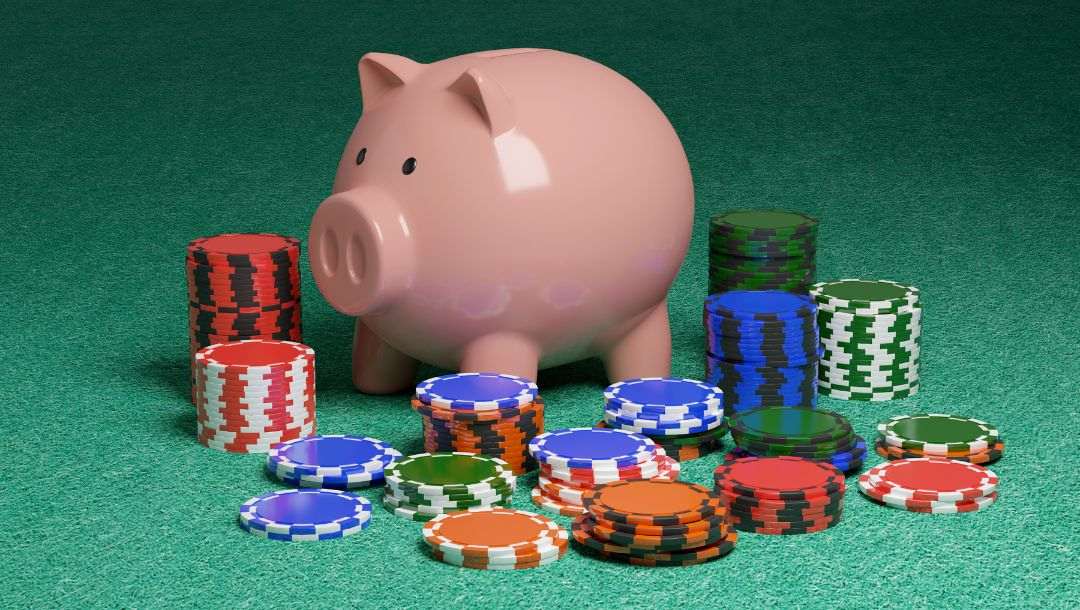 a pink piggy bank on a green felt poker surface surrounded by stacks of poker chips