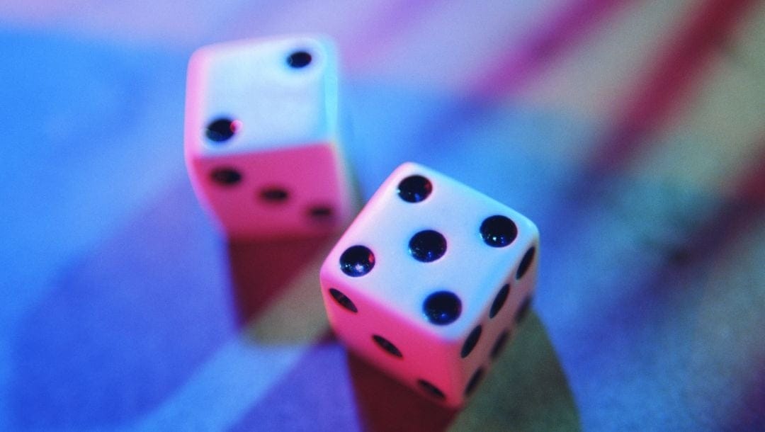 two white six-sided dice on a surface lit up with blue and pink ambient lighting