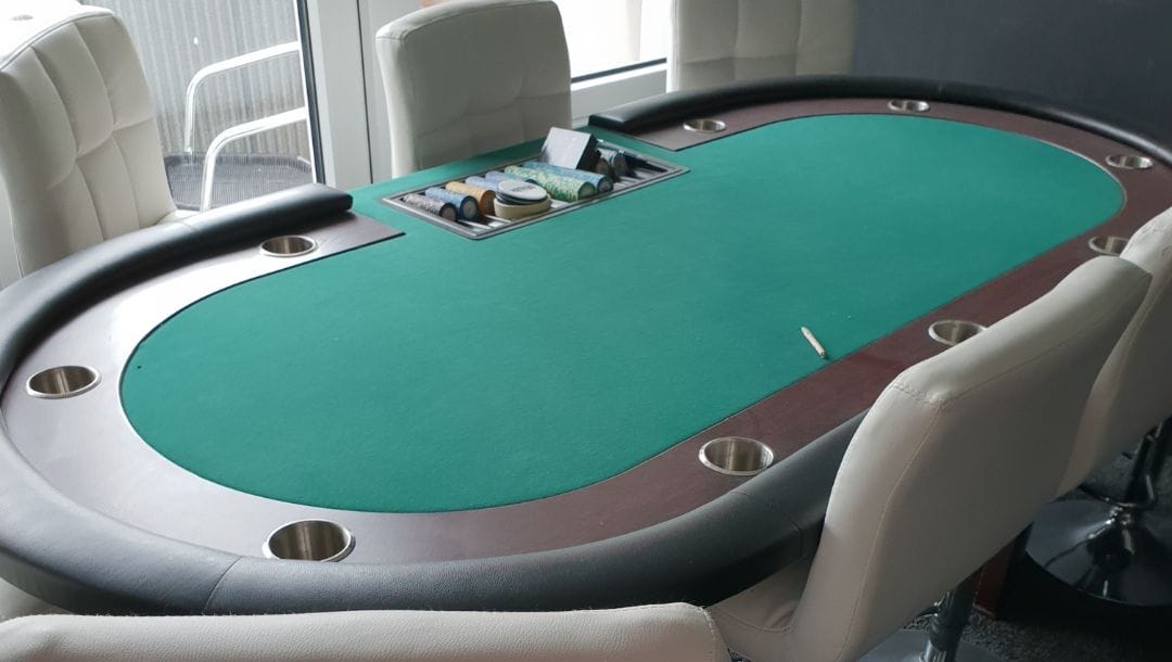 a casino poker table with cupholders and bar stools around it in a home