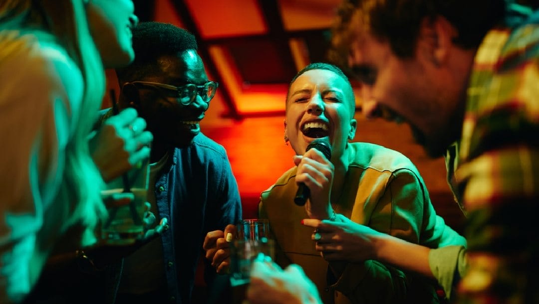 A person singing karaoke with a group of friends.