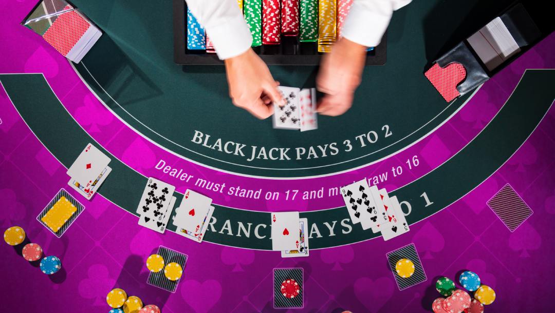 A blackjack dealer dealing out cards on a purple blackjack table.