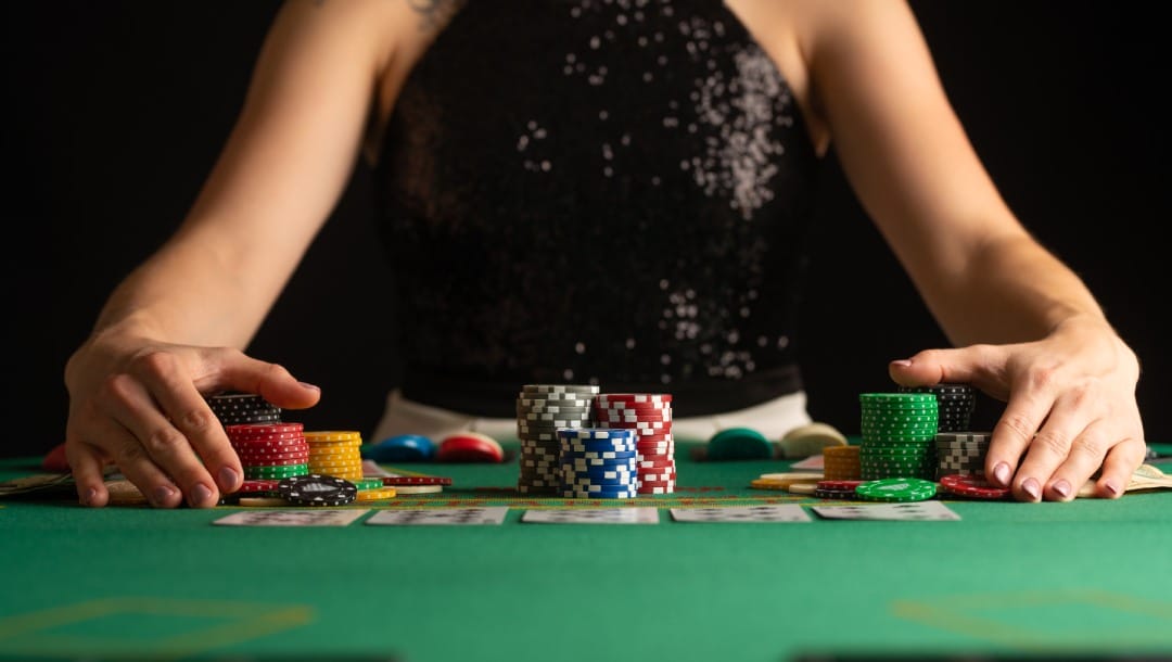 A casino player holding her hands over poker chips.